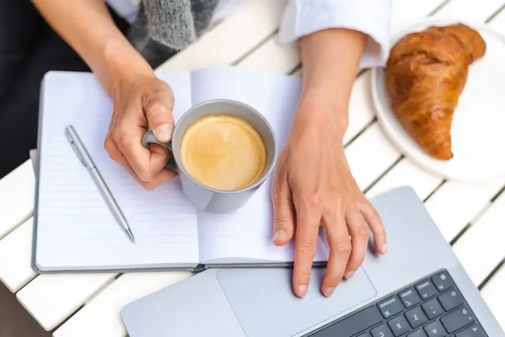 A woman works on a laptop whilst writing an email